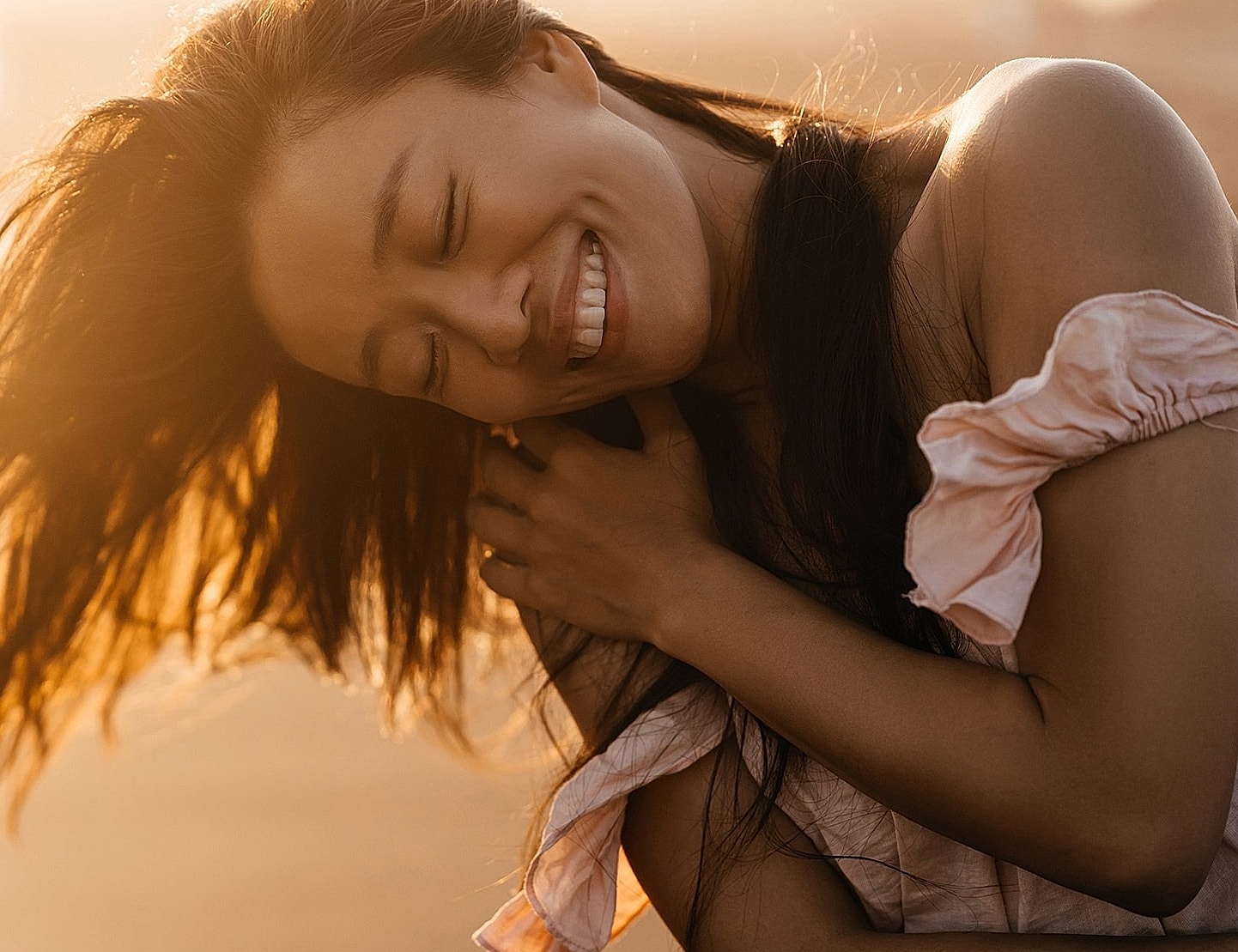 Smiling woman with flowing hair at sunset.