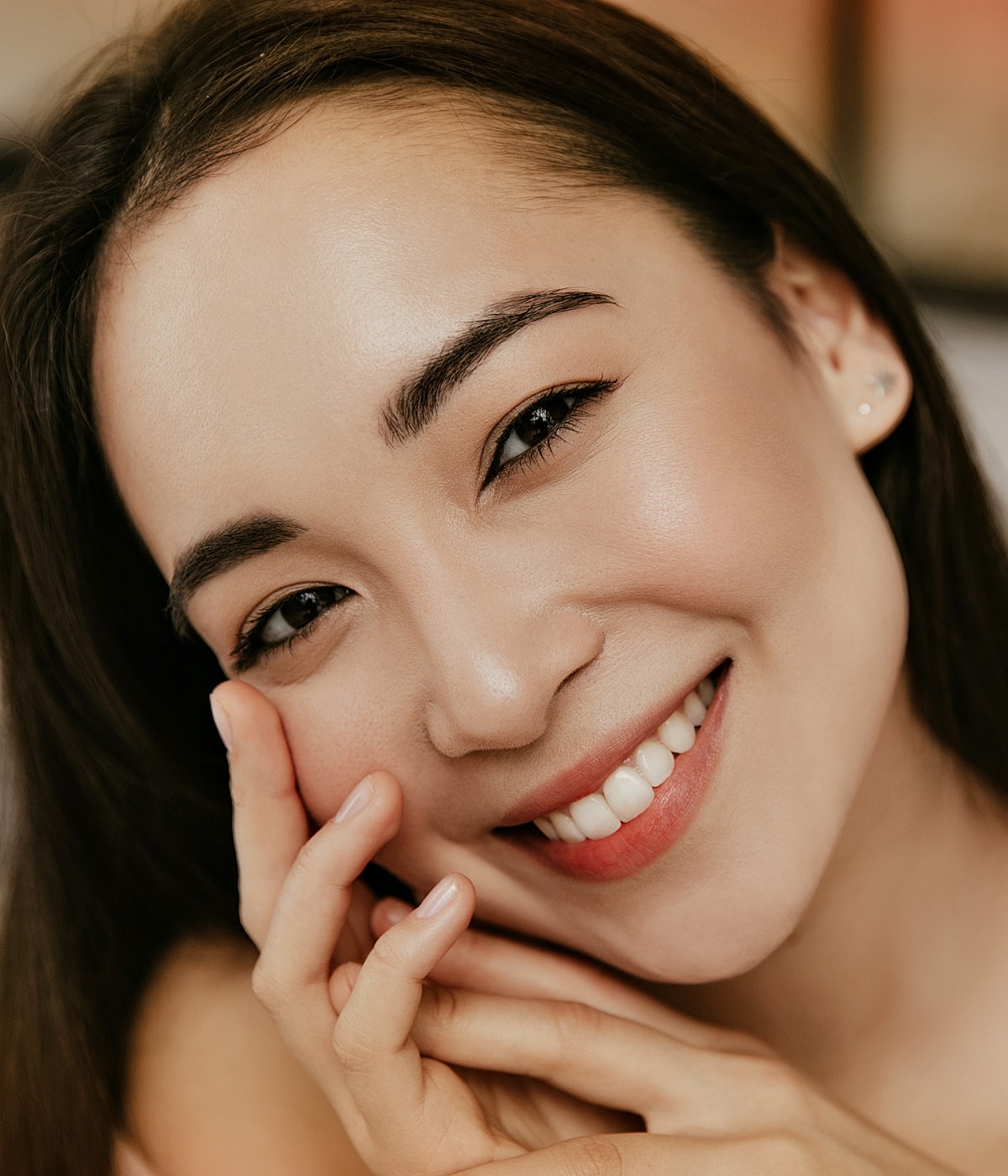 Smiling woman touching her face gracefully.