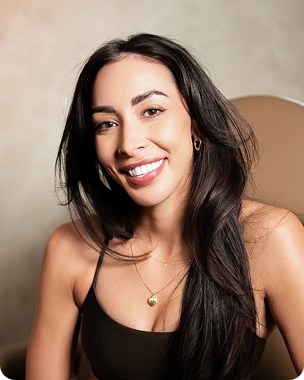 Smiling woman with long hair and jewelry.