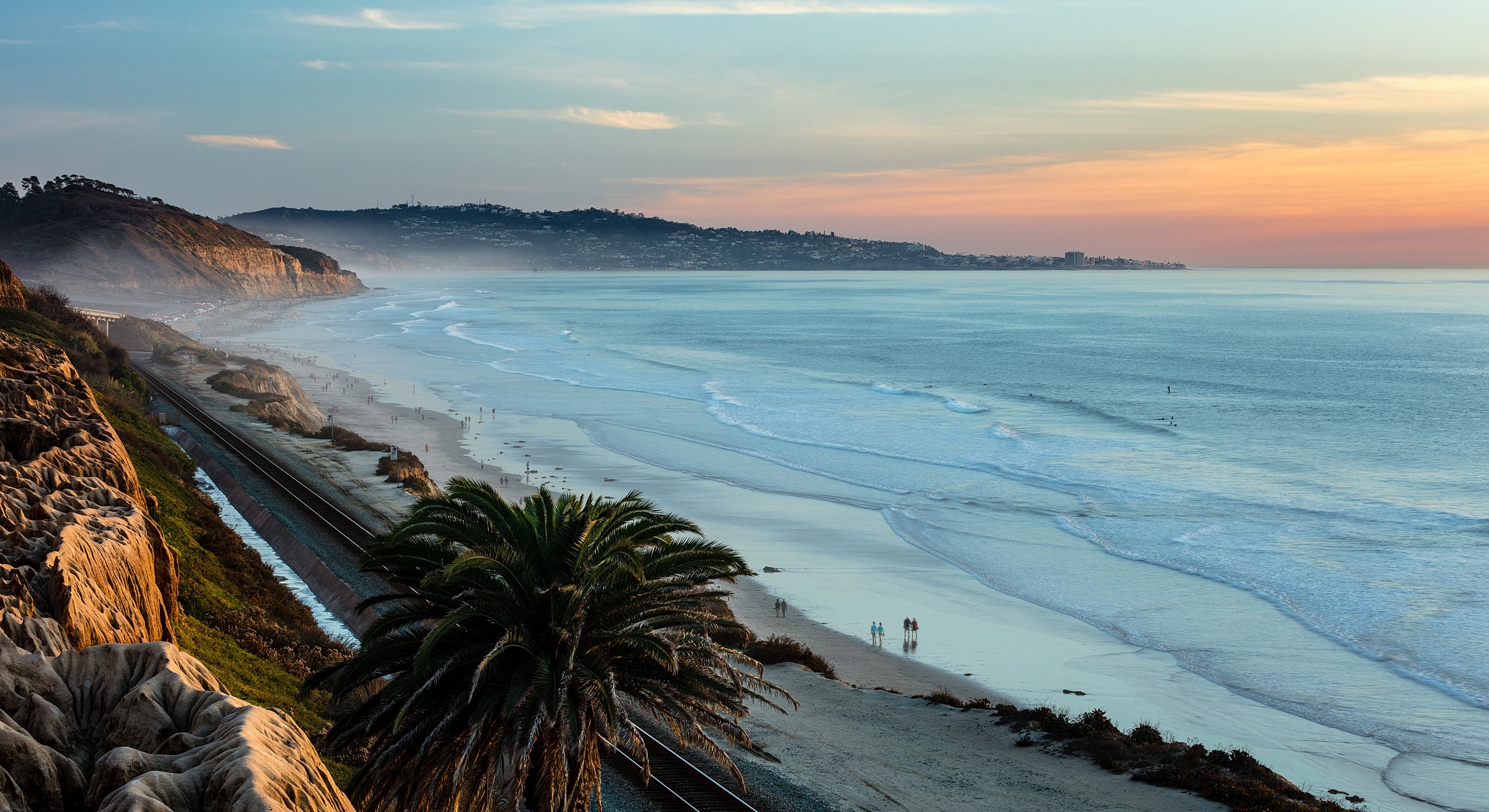 Coastal sunset view with palm and beach.