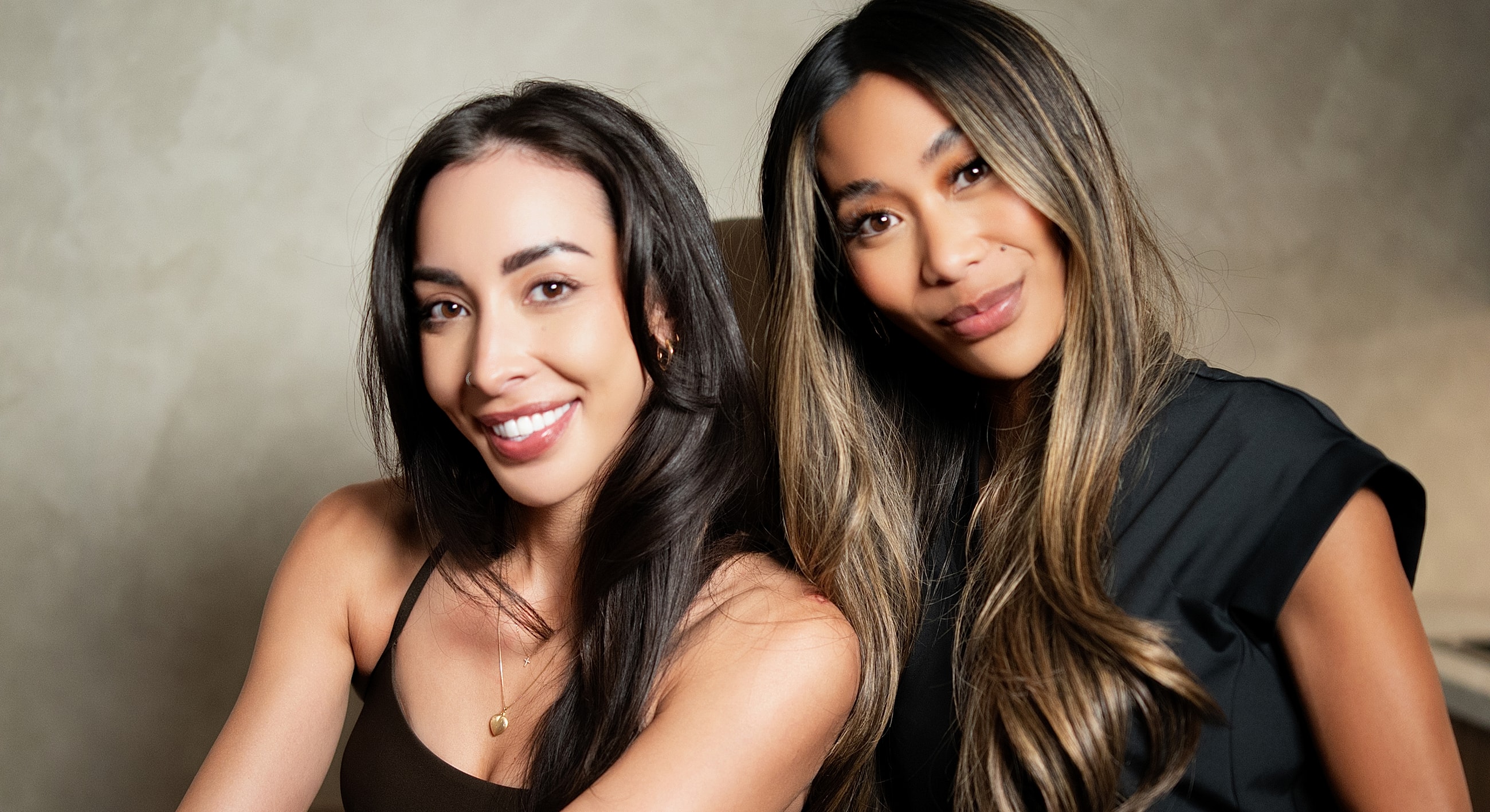 Two smiling women posing together indoors.