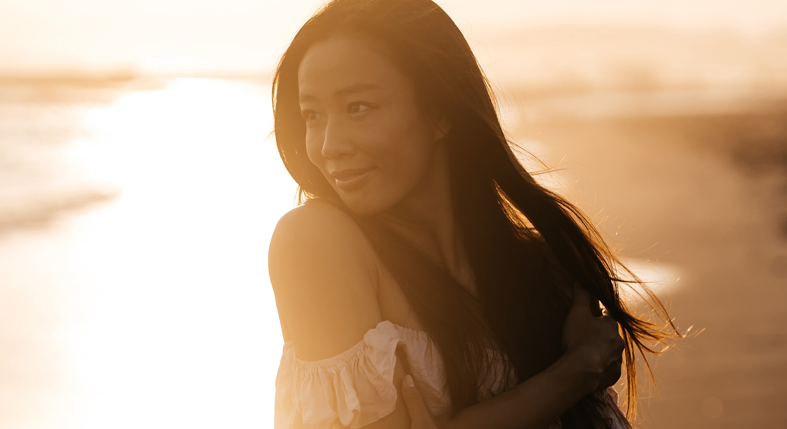 Woman with long hair by sunset beach.