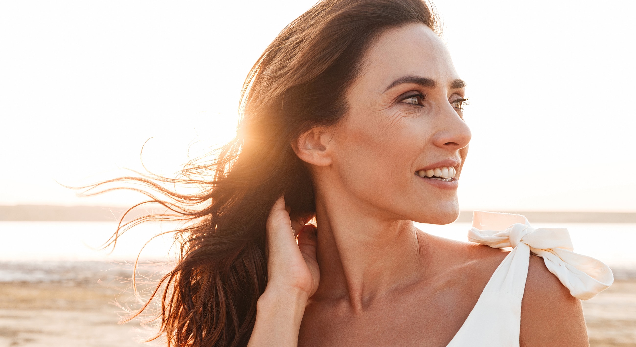 Woman smiling with sunlight in the background.